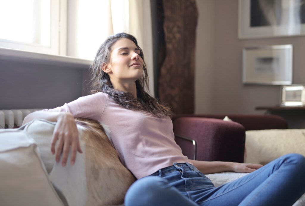 Woman relaxing on a couch in a cozy living room, embodying tranquility and comfort.